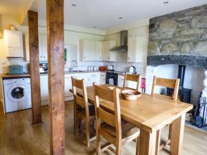 a kitchen with a wooden table with chairs and a stone wall at 2 Ysgubor Gerrig in Trefriw