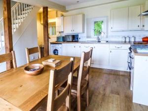 a kitchen with a wooden table with chairs and a counter at 2 Ysgubor Gerrig in Trefriw