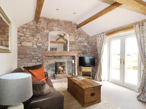 Faraway Cottage في Kirklinton: غرفة معيشة مع جدار حجري مع موقد