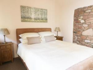 a bedroom with a large white bed with two lamps at Faraway Cottage in Kirklinton