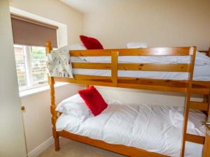 ウィットビーにあるOystercatcher Cottageのベッドルーム1室(二段ベッド2組、赤い枕付)
