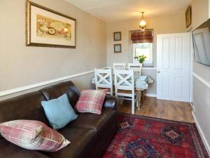 a living room with a leather couch and a table at Bwthyn Megan in Dwyran