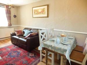 a living room with a couch and a table at Bwthyn Megan in Dwyran