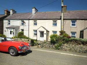 a red car parked in front of a house at Bwthyn Megan in Dwyran