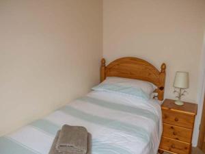 a bedroom with a bed and a dresser with a lamp at Post Box Cottage in Staithes