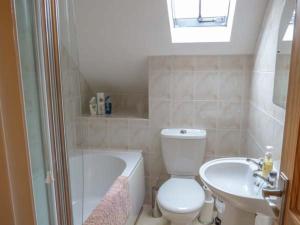 a bathroom with a toilet and a sink and a tub at Post Box Cottage in Staithes
