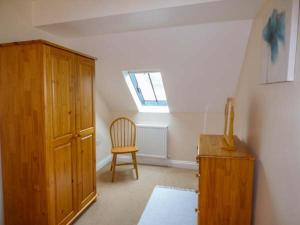 a room with a wooden cabinet and a chair at Post Box Cottage in Staithes