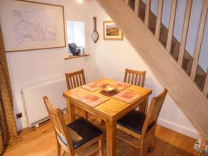 una mesa de madera y sillas en una habitación con escalera en Brig End en Langthwaite
