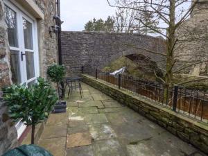 un patio con una mesa y una pared de ladrillo en Brig End en Langthwaite