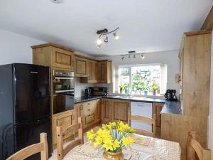 a kitchen with a table with yellow flowers on it at Simdda Wen Cottage in Llanddona