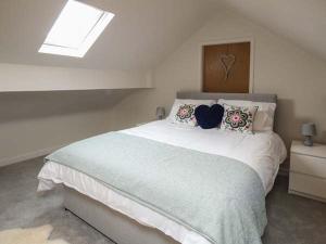 a bedroom with a large white bed with a window at Simdda Wen Cottage in Llanddona