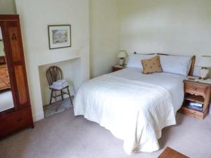 a bedroom with a white bed and a chair at The Conifers in Hutton Magna