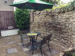 a table with a green umbrella and two chairs at The Conifers in Hutton Magna