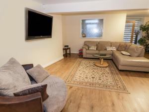 a living room with couches and a flat screen tv at Yr Hen Fanc in Benllech