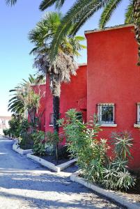 a red building with a palm tree next to a street at Rés Marea Resort, Santa-Lucia-di-Moriani, 2 room apt in Santa-Lucia-di-Moriani