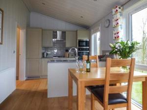 a kitchen with a wooden table and a table and chairs at Shepherd Lodge in Cartmel