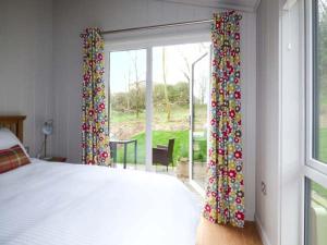a bedroom with a bed and a window with curtains at Shepherd Lodge in Cartmel