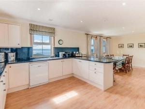 a kitchen with white cabinets and a table in it at Little Laight in Cairnryan