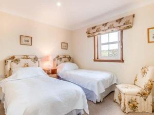 a bedroom with two beds and a window and a chair at Little Laight in Cairnryan