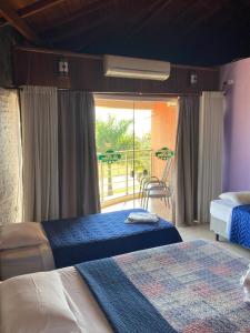 1 dormitorio con 2 camas y balcón en La Palma Hotel Fazenda, en Indaiatuba