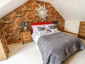 1 dormitorio con cama y pared de ladrillo en 1 The Old Smithy, en Cemaes