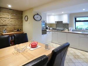 a kitchen with a table and a clock on the wall at Woods View Cottage in Tansley