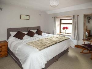 a bedroom with a large white bed and a window at Woods View Cottage in Tansley