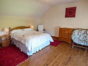 a bedroom with a bed and a dresser and a chair at Ysgubor - Barn in Llanddulas