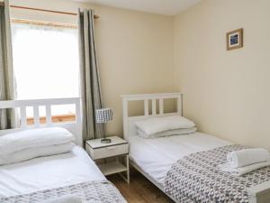 Duas camas num pequeno quarto com uma janela. em 79 Corrour Road em Aviemore