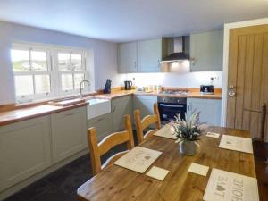 a kitchen with a wooden table and a table and chairs at Little Owl Barn in Warslow