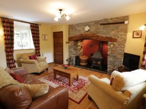 a living room with a stone fireplace and leather furniture at Hafan in Llanerfyl