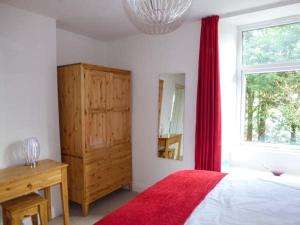 a bedroom with a bed with a red blanket and a window at Crooklands House 3 in Crooklands