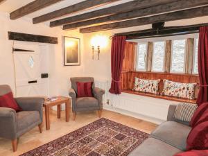a living room with two chairs and a table and a window at Sundial Cottage in Brassington