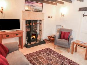 a living room with a fireplace and a tv at Sundial Cottage in Brassington