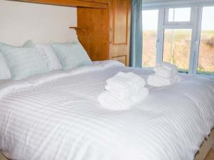a white bed with three rolls of towels on it at Smugglers' Cottage in Marske-by-the-Sea