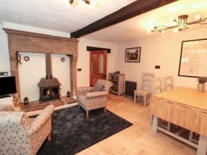 a living room with a fireplace and a table and chairs at Sundial Cottage in Brassington