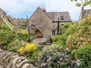 a garden in front of a stone house with flowers at Sundial Cottage in Brassington