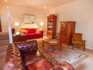 a living room with a leather couch and a red couch at Poacher's Rest in Great Rowsley