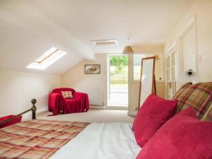 a bedroom with a bed and a red chair at Poacher's Rest in Great Rowsley