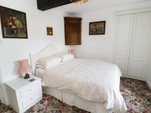 a white bedroom with a bed and a night stand at Sally's Cottage in Carleton