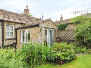 an old stone house with a garden in front of it at Sally's Cottage in Carleton