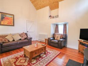 a living room with two couches and a tv at Rosslare Cottage in Broughshane