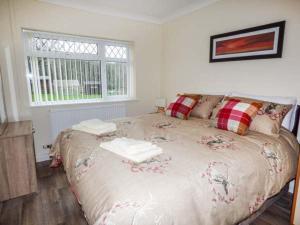 a bedroom with a large bed with pillows and a window at Cwm Gran Meadows in Llanharan