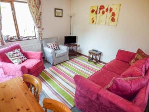 a living room with two pink couches and a table at The Old Parlour in Winford