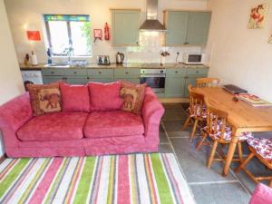 a living room with a pink couch in a kitchen at The Old Parlour in Winford
