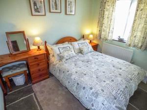 a bedroom with a bed and a dresser and a mirror at The Old Parlour in Winford