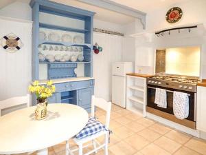 eine Küche mit einem weißen Tisch und einem blauen Schrank in der Unterkunft Blue Harbour Cottage in Torquay