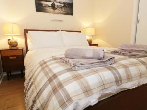 ein Schlafzimmer mit einem Bett mit zwei Lampen und zwei Handtüchern in der Unterkunft Bungalow in Fishguard