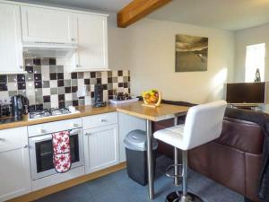 a kitchen with white cabinets and a table and a couch at Fortunatus in Whitby