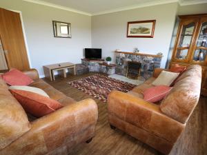 a living room with two couches and a fireplace at Pen Y Cae in Llansannan